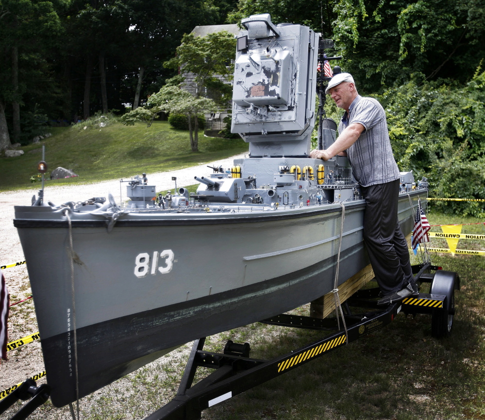Steve MacDonald of Hingham poses with his 20-foot-long model of World War II battleship USS Charles Dean in Cohasset, Mass. MacDonald is selling the intricate replica for $10,000. The boat can be taken out on water.