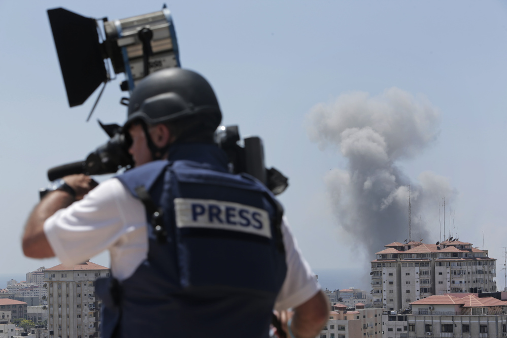 A news cameraman films at a live position as in the background smoke rises from an Israeli strike in Gaza City, Sunday.