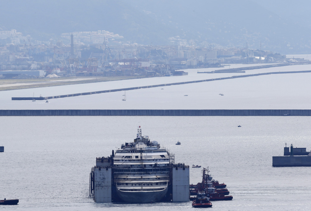 The wreck of the Costa Concordia cruise ship is towed by tugboats towards Genoa’s harbor, Italy, Sunday.