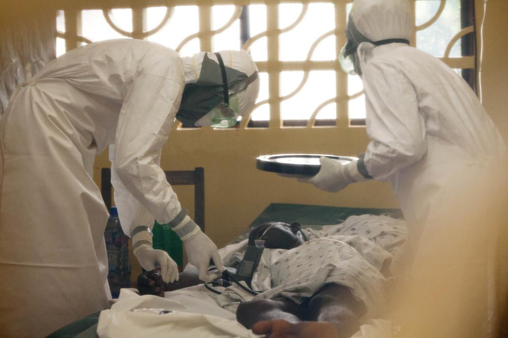 In this 2014 photo provided by the Samaritan’s Purse aid organization, Dr. Kent Brantly, left, treats an Ebola patient at the Samaritan’s Purse Ebola Case Management Center in Monrovia, Liberia.
