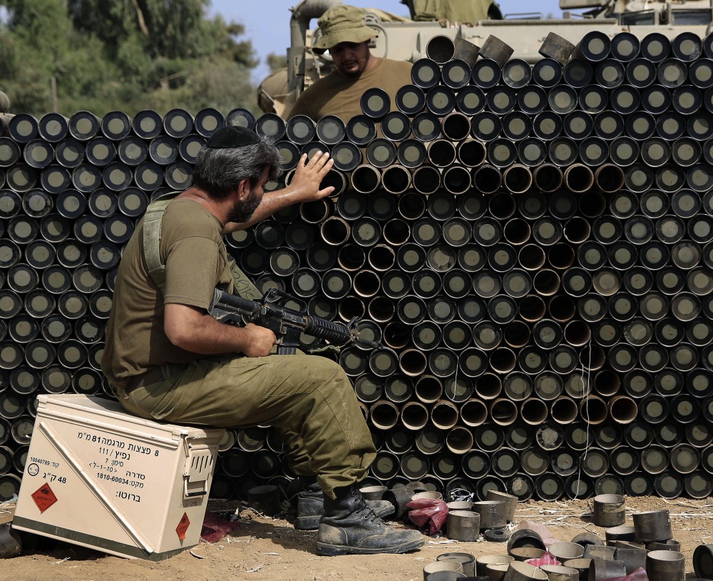 An Israeli reserve soldier makes a Star of David pattern from cardboard mortar shell boxes near the Israel-Gaza border on Monday. A truce between Israel and Hamas militants in Gaza remains elusive as Secretary of State John Kerry continues to work for a cease-fire.