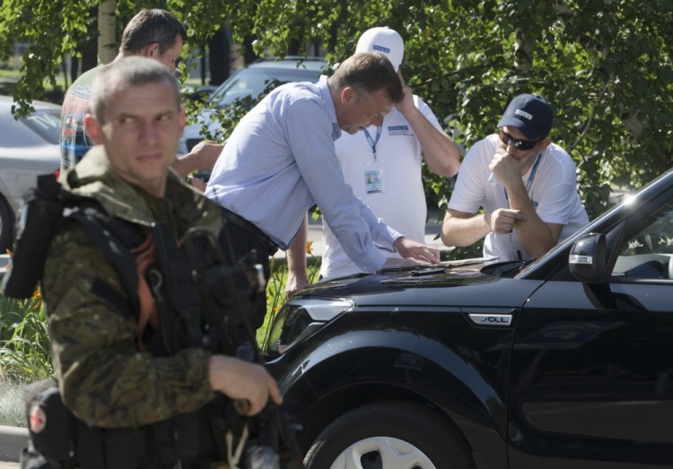 Alexander Hug, deputy head of the OSCE mission to Ukraine, center, and his colleagues examine a map as they discuss the situation around the site of the crashed Malaysia Airlines Flight 17, in the city of Donetsk, eastern Ukraine Wednesday.