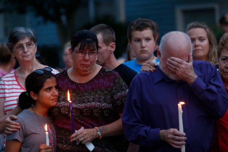 Becca Garland comforts her neighbor Youna Karim, 12, during a vigil for the Smith family at the RiverView apartments in Saco on Tuesday night, while Joel Smith's father, Steve Smith, covers his face.  Garland said, "I was her best friend here," speaking of Heather Smith, one of the victims. "We had a barbeque on Saturday night and I kissed her and told her 'I love you and I will see you tomorrow.'"