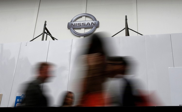 People walk past a wall set up in front of Nissan's showroom under renovation in Tokyo, Monday, May 12, 2014. The Associated Press
