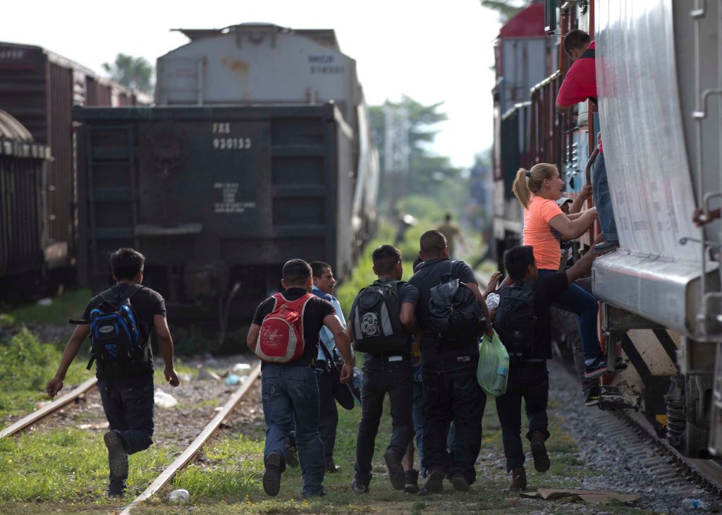 immigrants run to jump on a train during their journey toward the U.S.-Mexico border, in Ixtepec, Mexico, on July 12. 