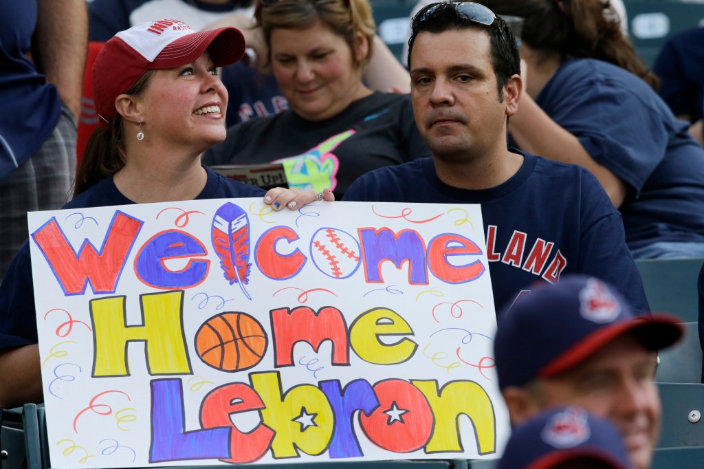 A Cleveland Indians fan holds a sign welcoming LeBron James back to the city, before Friday's baseball game between the Chicago White Sox and the Indians. Officials say James' return will mean hundreds of millions of dollars in economic benefit to Cleveland and Northeast Ohio.