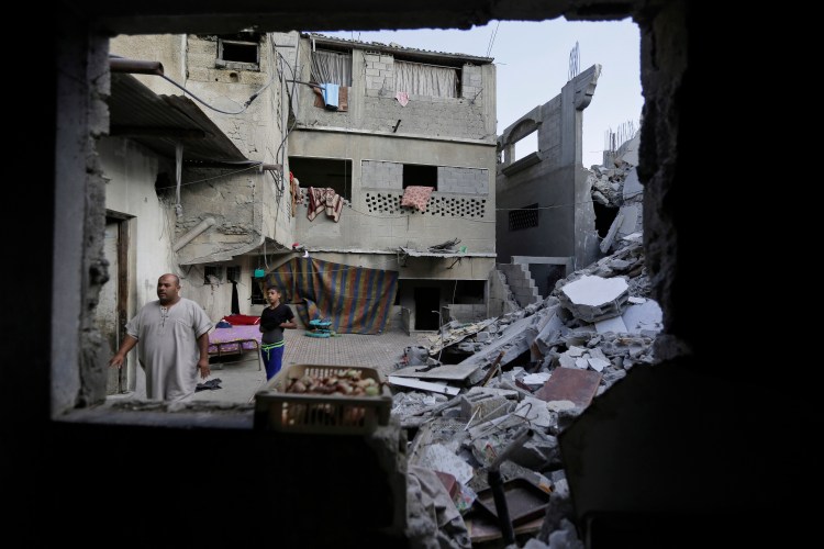 Palestinian Bajes Jendiyah, left, walks past the rubble of his family house, partially destroyed by an Israeli strike, in the Sabra neighborhood of Gaza City on Thursday. Israel and Hamas agreed Thursday to a 72-hour cease-fire starting Friday.