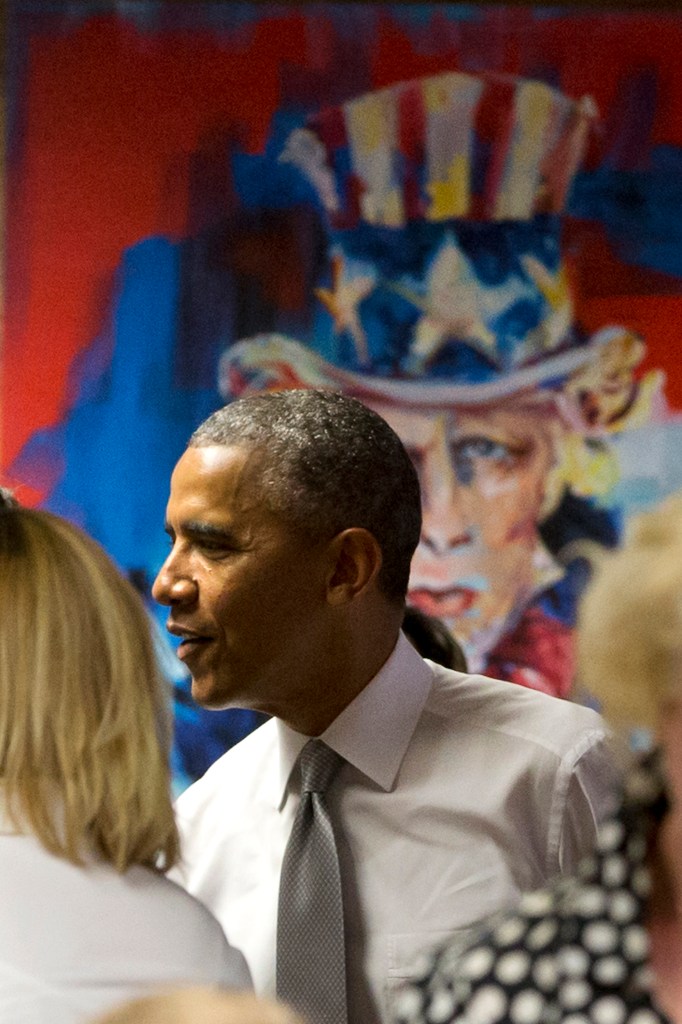 President Barack Obama stands by a painting of "Uncle Sam," as he meets with workers at 1776, a hub for tech startups, Thursday, July 3, 2014, in Washington, where he spoke. The president said  job growth in June shows the recovery is taking hold, but the economy could still do better, he also urged Congress to work with him to help create more jobs.  