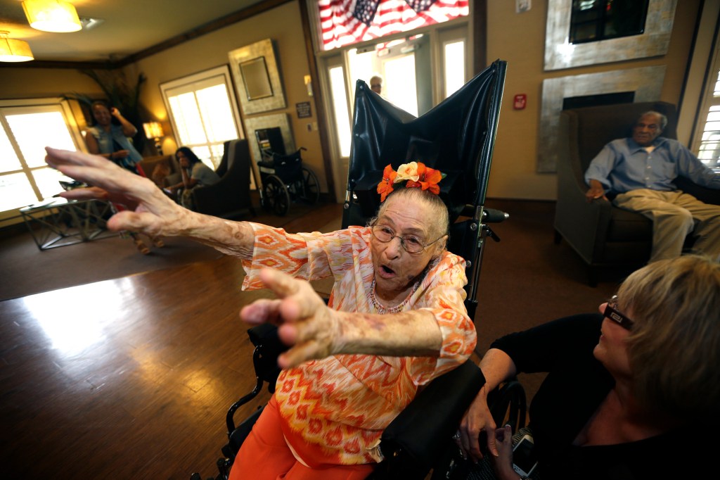 In this photo taken Thursday, July 3, 2014, Gertrude Weaver, who turns 116 July 4, raises her arms as she calls the hogs at Silver Oaks Health and Rehabilitation Center in Camden, Ark.