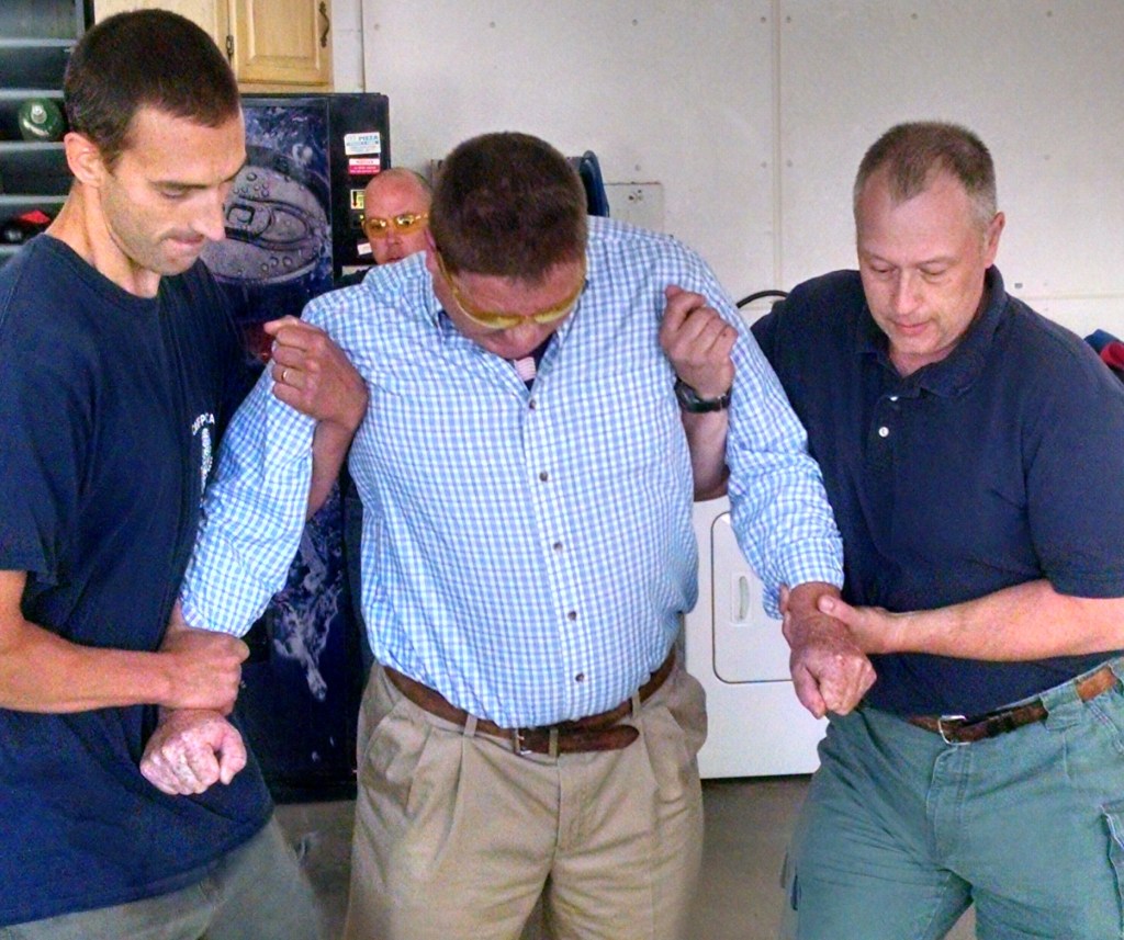 Fryeburg Selectman Paul Naughton is assisted by Bridgton police Officer Phillip Jones, left, and Fryeburg fire Lt. Mike McAllister while being Tasered during a certification program Monday.