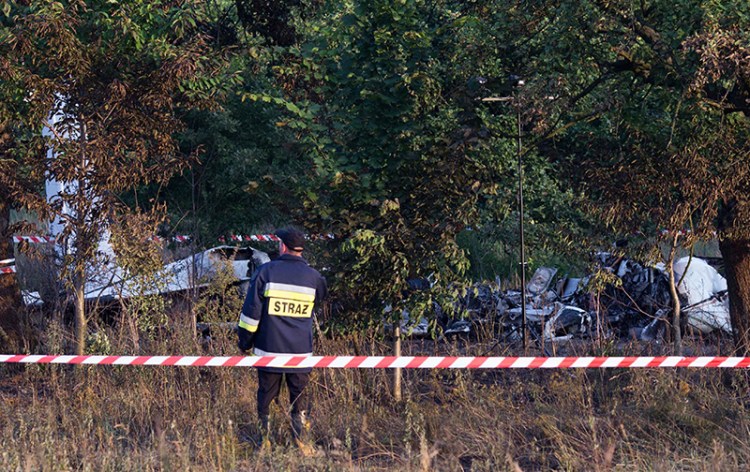 A firefighter officer examines the crash site of a plane near the village of Topolow in Poland, Saturday. The Associated Press