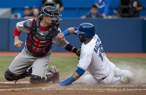 Blue Jays first baseman Jose Bautista slides past Red Sox catcher Christian Vazquez at home plate to score a run in the first inning Wednesday in Toronto. The Associated Press
