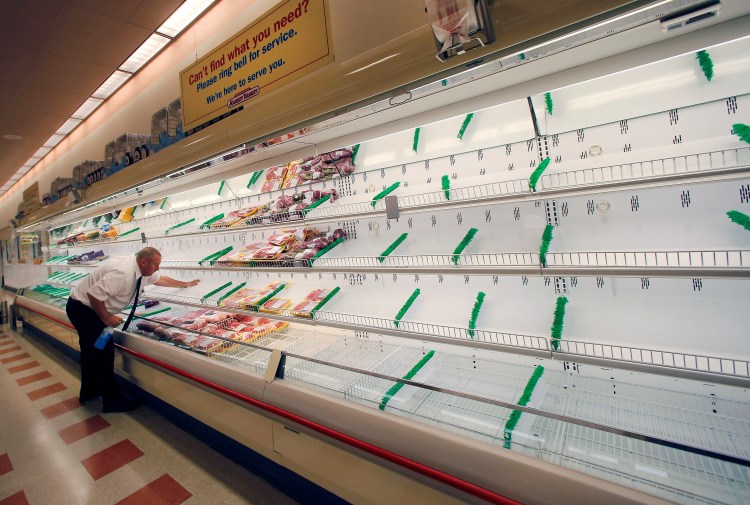 Meat manager Dave Fillebrown wipes down largely empty shelves last week at a Market Basket supermarket in Haverhill, Mass. The Associated Press