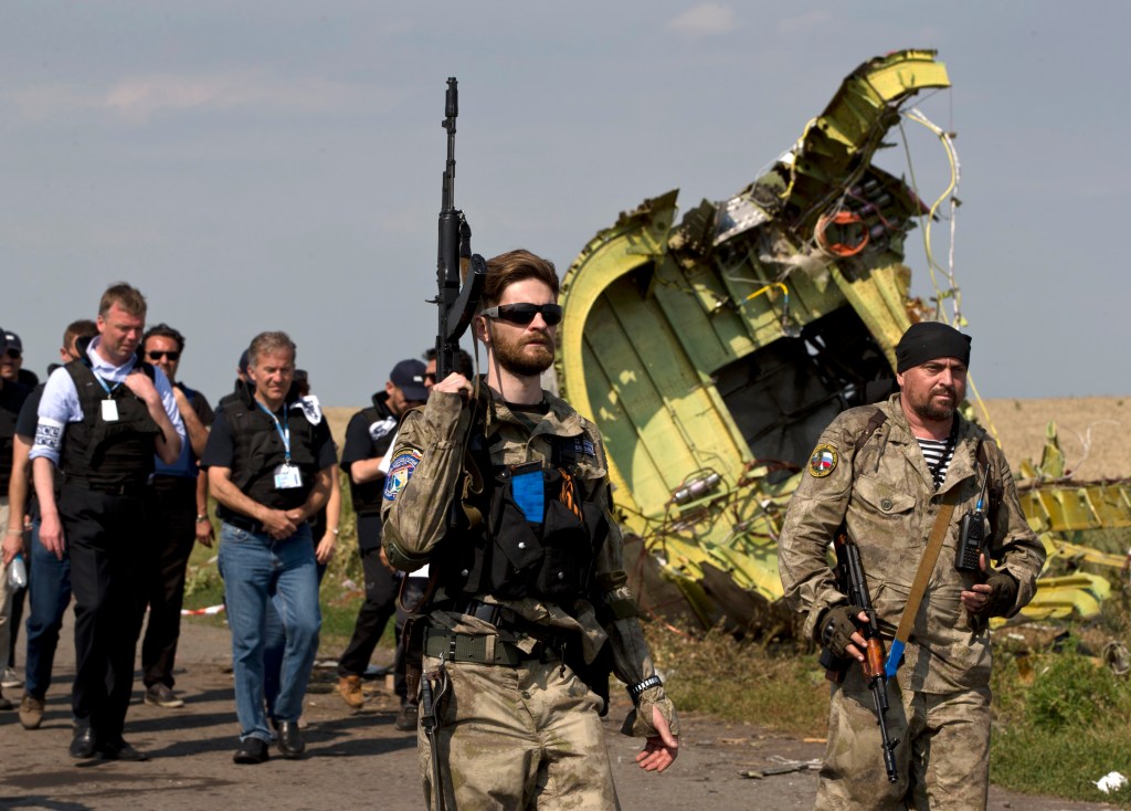 Pro-Russian rebels, followed by members of the OSCE mission, walk by plane wreckage as they arrive for a media briefing at the crash site of Malaysia Airlines Flight 17, near the village of Hrabove, eastern Ukraine, on Tuesday. A team of Malaysian investigators visited the site along with members of the OSCE mission for the first time since last week's crash.
