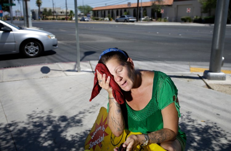 Amanda Ouellet wipes her face with a wet towel to cool off while working outside holding an advertising sign in Las Vegas in this n this July 1, 2014, photo. About 31 percent of the weather-related deaths in the U.S. between 2006 and 2010 were caused by heat, heat stroke or sun stroke, according to the CDC. The Associated Press