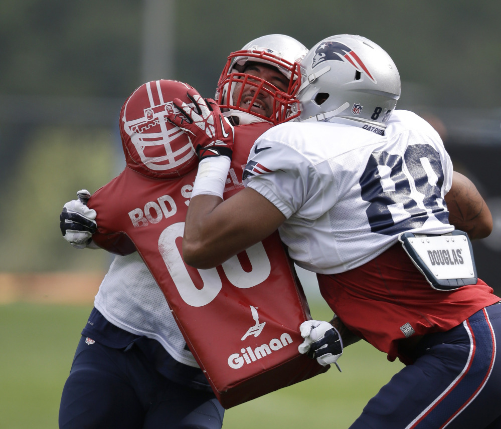 New England Patriots tight end Michael Hoomanawanui, left, grapples with tight end Justin Jones, right, during a field exercise in an NFL football training camp practice at Gillette Stadium on Sunday in Foxborough, Mass. The Associated Press
