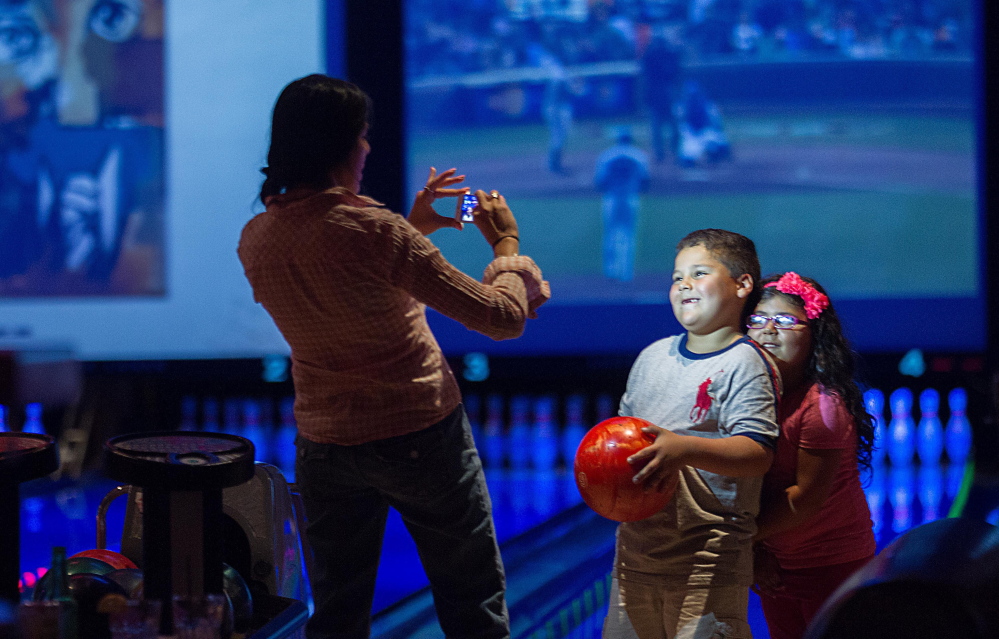 Jacqueline Martinez takes a picture of her son Ryan, 6, and daughter Isabel, 4, as they bowl at Lucky Strike in Chicago.