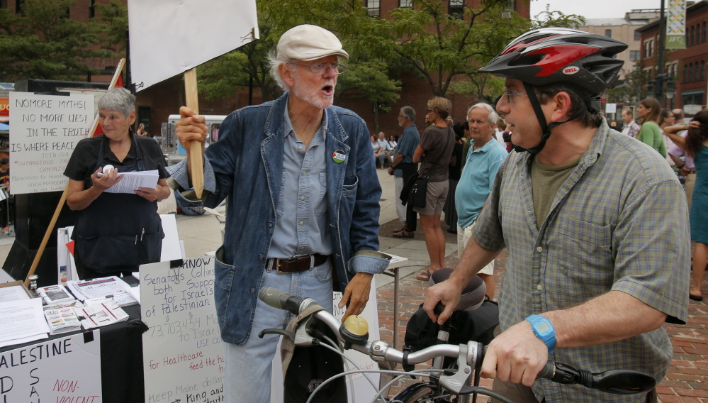 Bob Schaible, left, was protesting in support of Palestinians on Friday night when Natan Khan was riding through Congress Square with his two sons and felt compelled to stop and defend Israel’s actions in the Gaza Strip.