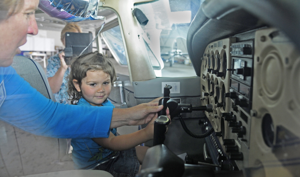 Lisa Reece, president of Maine Aeronautics, left, shows Karen Munzing, 3, the controls of a plane during an Amelia Earhart event Saturday at the Augusta State Airport.
