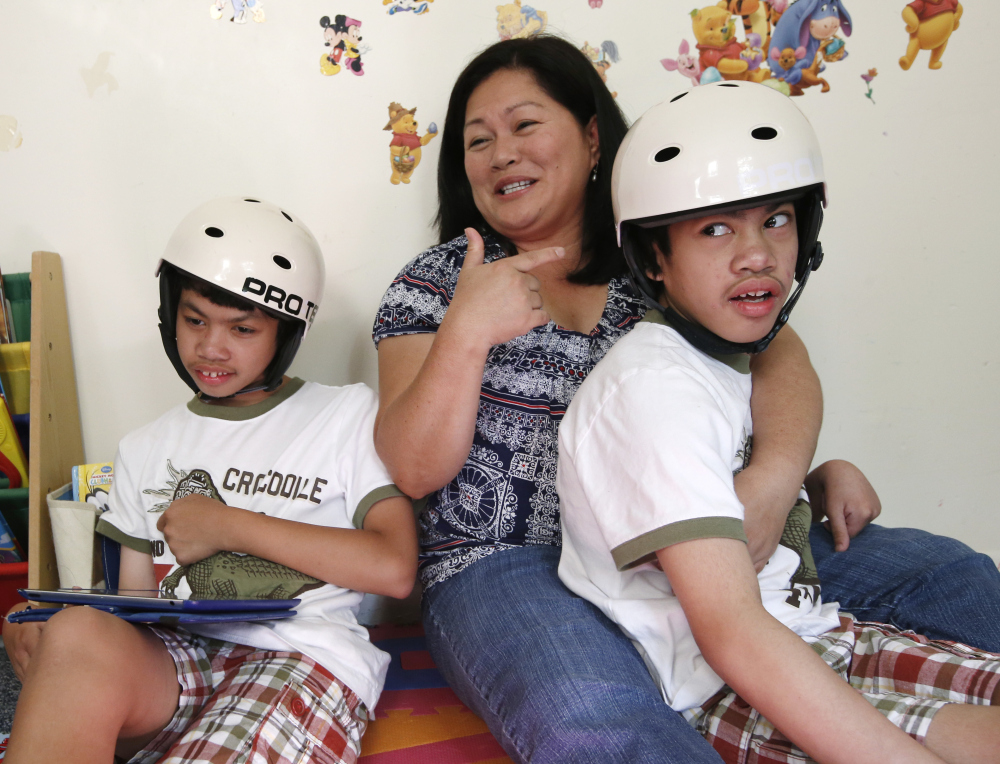 Arlene Aguirre, center, sits with her 12-year-old twin sons Carl, left, and Clarence in Scarsdale, N.Y., on Thursday. On Monday, Montefiore Hospital and the family will celebrate the 10th anniversary of the surgery that separated the boys who were born conjoined.