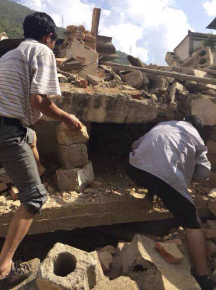 In this cellphone photo released by China’s Xinhua News Agency, men scramble amid the rubble of buildings as they look for survivors after an earthquake in Ludian on Sunday.