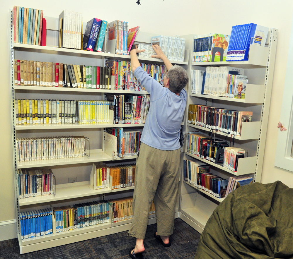 Board of trustees member Bonnie Dushin straightens books in the young adult area at the new Umberhine Public Library in Richmond.