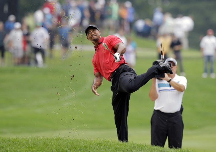 Tiger Woods makes an awkward follow through after hitting from the lip of a fairway bunker on the second hole during the final round of the Bridgestone Invitational golf tournament Sunday,  at Firestone Country Club in Akron, Ohio. The Associated Press