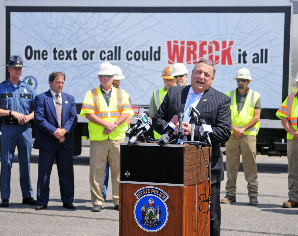Gov. Paul LePage stands in front of a truck with the words “One text or call could wreck it all,” as he talks about distracted driving on Tuesday during a news conference in the parking lot outside State Police headquarters in Augusta.