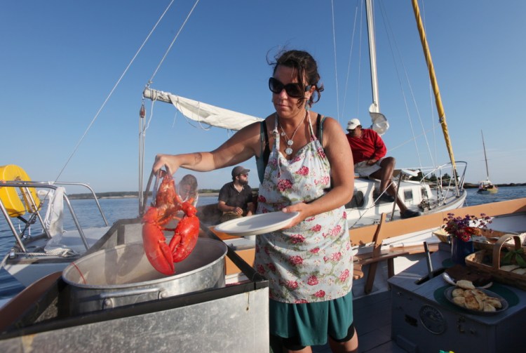 Reilly Harvey pulls a cooked lobster from a pot on board her boat Mainstay in the harbor between Dix Island and High Island.