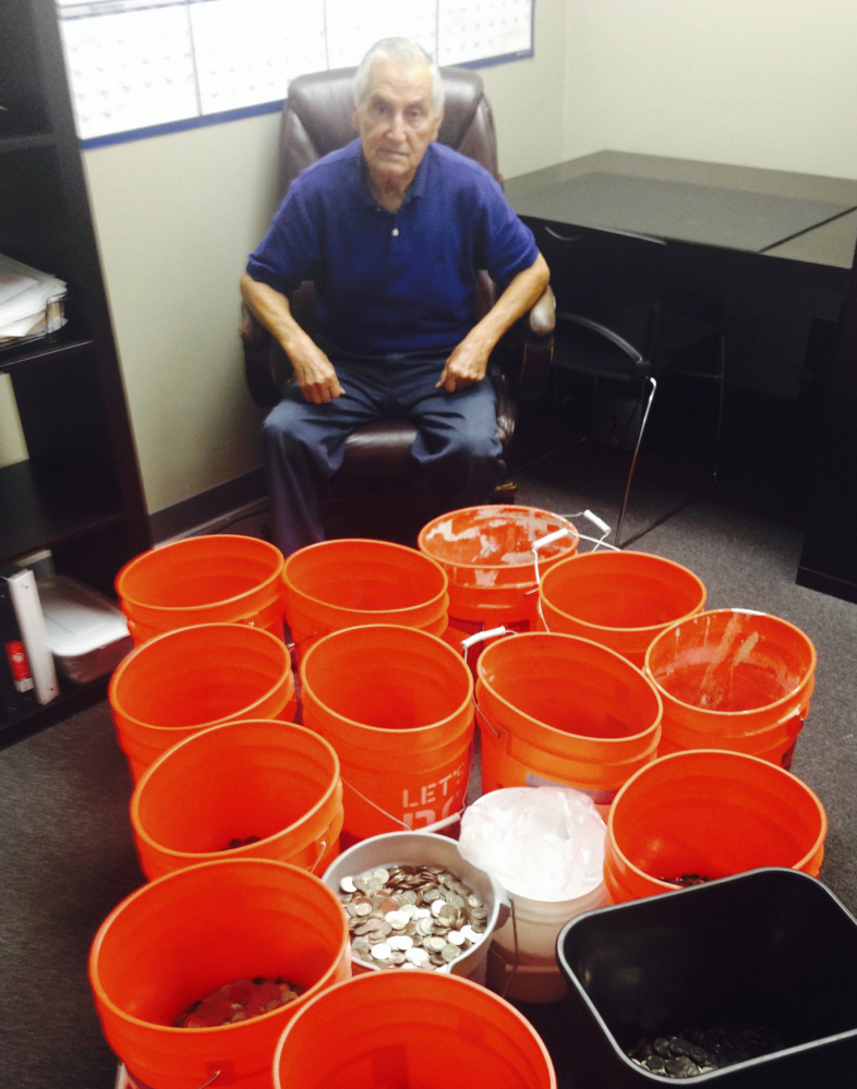 Andres Carrasco sits in his Los Angeles office with buckets of change totaling more than $20,000 that he received as a partial settlement in his suit against an insurance company.