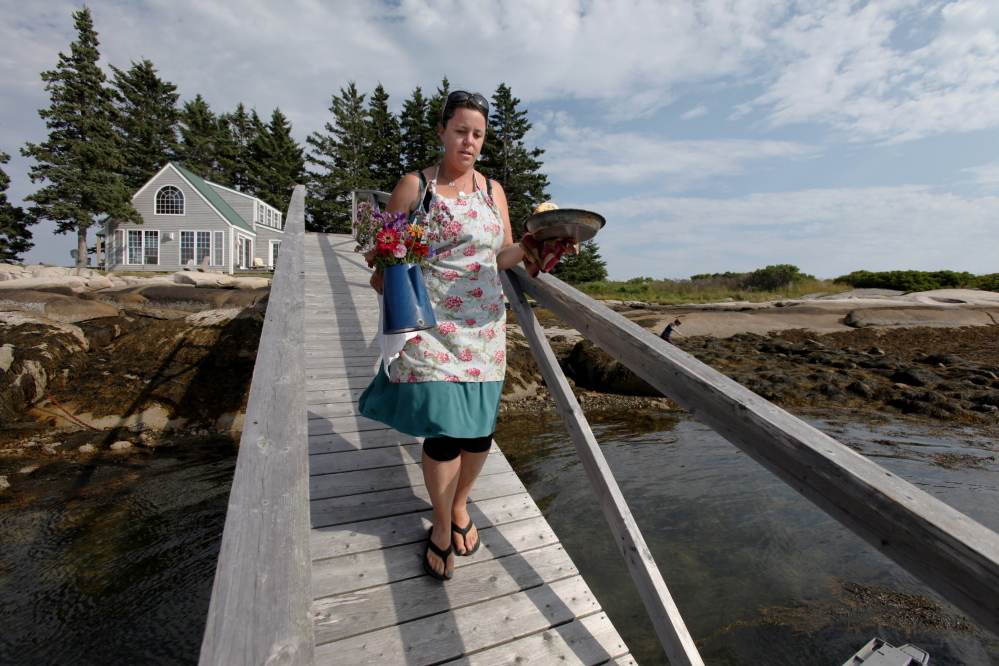 Entrepreneur Reilly Harvey carries flowers and biscuits down the ramp from her house on Andrews Island to her boat. Her seasonal business, Mainstay Provisions, must remain closed until it complies with health code regulations for mobile vendors.