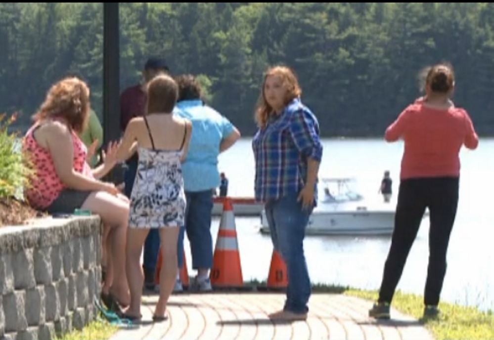 Spectators gather on shore as rescuers search the Penobscot River after a boy fell in and his grandfather jumped in to try to save him Friday morning.
