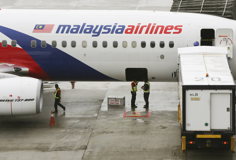 Ground crew members stand near a Malaysia Airlines aircraft at the Kuala Lumpur International Airport in Sepang, Malaysia, last May. Malaysia’s state investment company said Friday that it plans to remove struggling Malaysia Airlines from the stock exchange, making it fully state-owned.