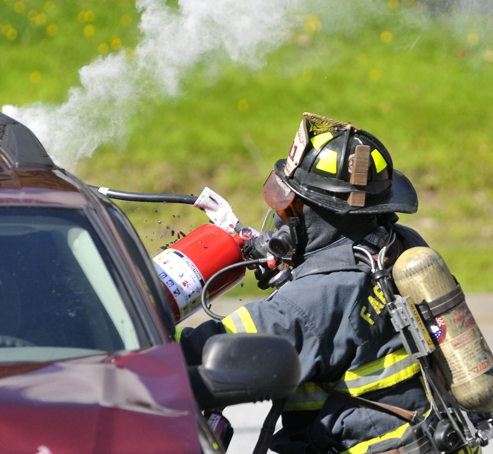 A Farmington firefighter breaks a vehicle’s window during the Homeland Security training exercise Friday.