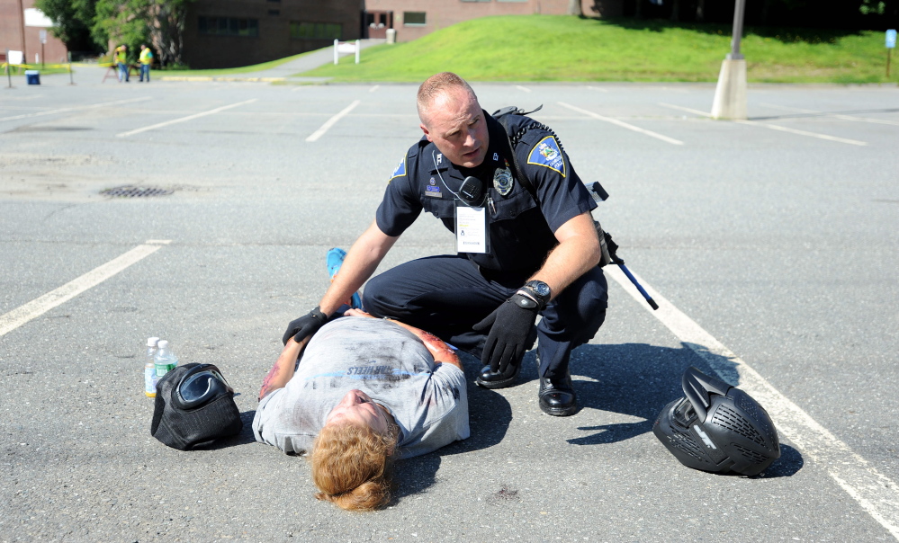 Darin Gilbert, Farmington police officer, tends to  a person portraying a car bombing victim in the parking lot at the University of Maine at Farmington during a Homeland Security training event Friday.