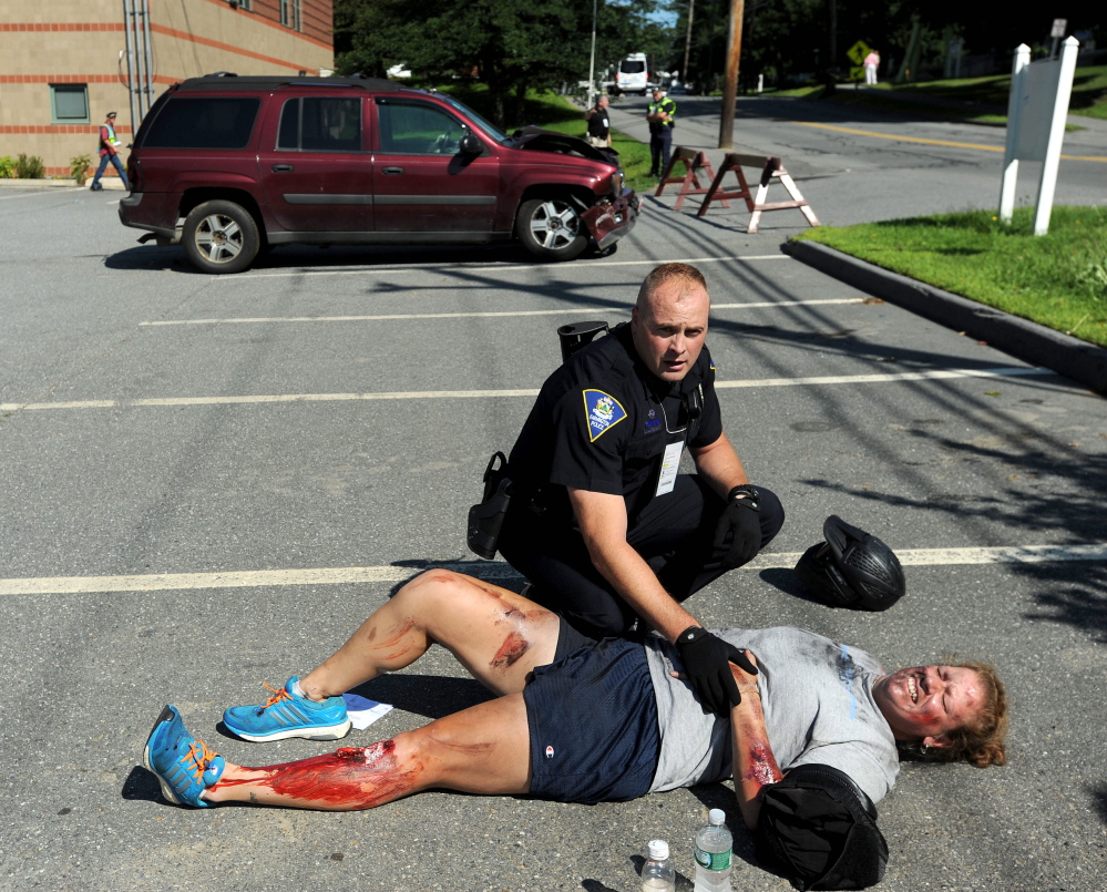 Darin Gilbert, Farmington police officer, tends to  person portraying a car bombing victim in a parking lot at the University of Maine at Farmington during a large-scale Homeland Security training exercise.