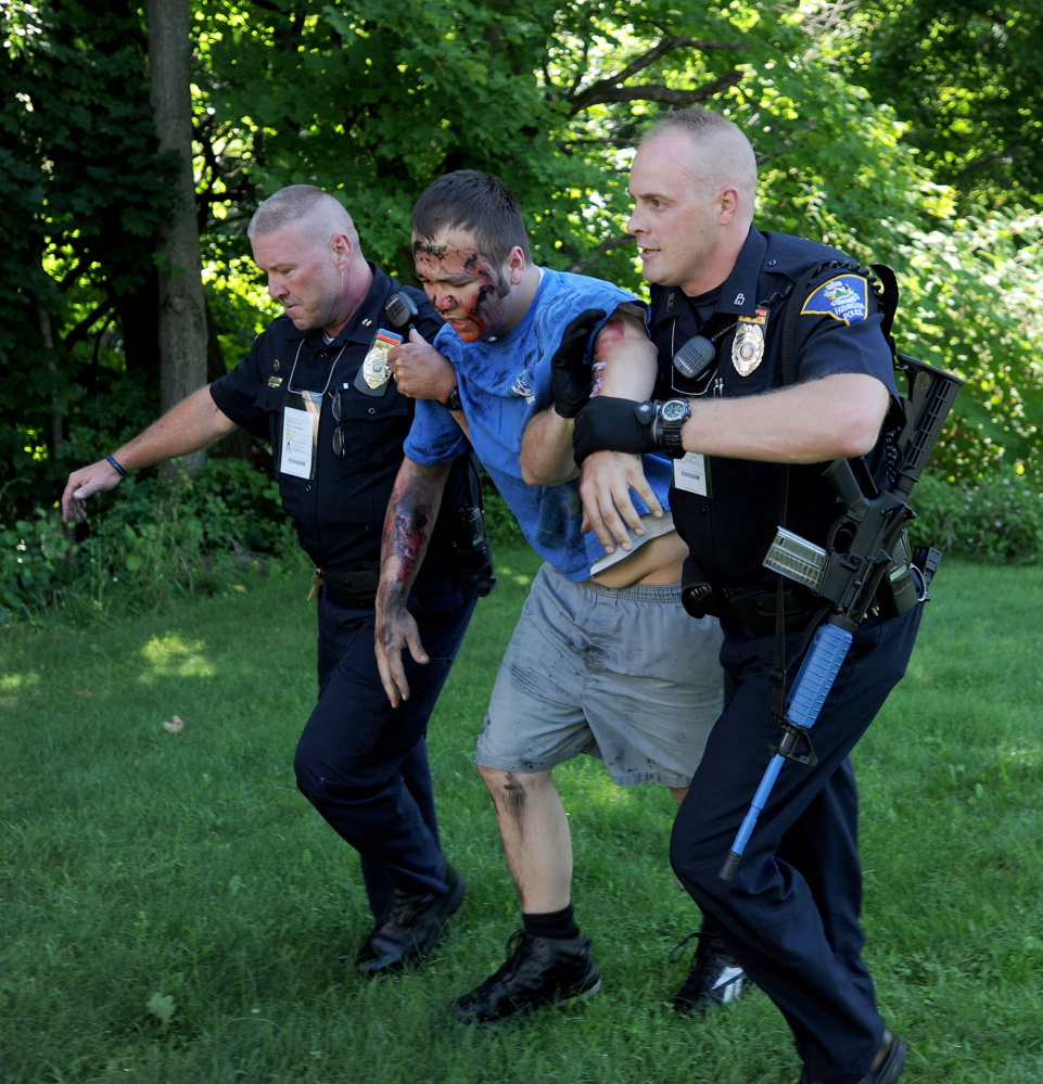 Farmington Police Chief Jack Peck, far left and officer Darin Gilbert, far right, help a person portraying a victim of a car bombing on Friday.