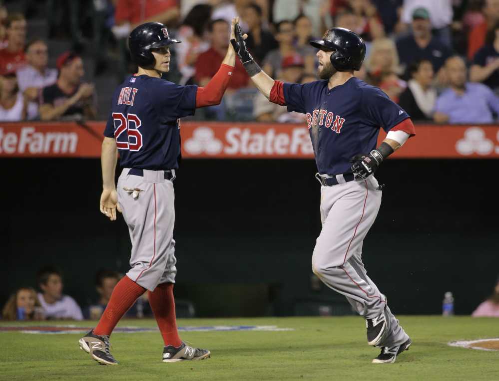 Boston’s Brock Holt, left, and Dustin Pedroia celebrate after scoring on a double by Yoenis Cespedes in the third inning against the Los Angeles Angels on Friday in Anaheim, Calif.