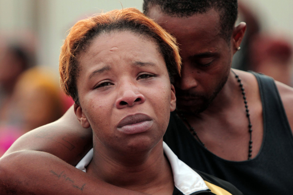 Lesley McSpadden, left, is comforted by her husband, Louis Head, after her 18-year-old son, Michael Brown was shot by police and killed in the middle of the street in Ferguson, Mo., near St. Louis on Saturday.