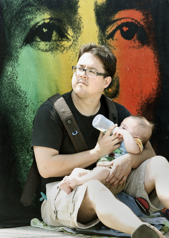 Tai Choo of Brunswick feeds his 5-month-old baby, Mateo, in front of a Bob Marley blanket.