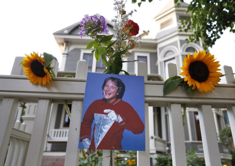 A photo of the late actor Robin Williams as Mork from Ork hangs with flowers left by people paying their respects, in Boulder, Colo., Monday.