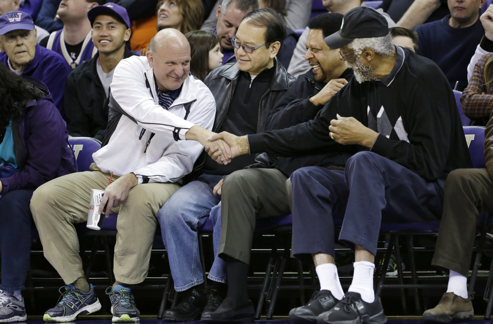 In this Jan. 25, 2014, photo, then-Microsoft CEO Steve Ballmer, left, shakes hands with former NBA players Bill Russell, right, and “Downtown” Freddie Brown as Omar Lee looks on during an NCAA college basketball game between Washington and Oregon State in Seattle.