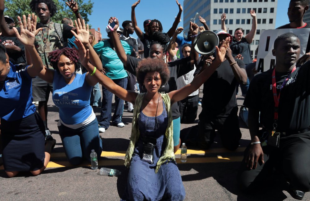 Protesters drop to their knees and raise their arms during a rally in Clayton, Mo., on Tuesday for Michael Brown Jr., who was shot and killed by a police officer Saturday.