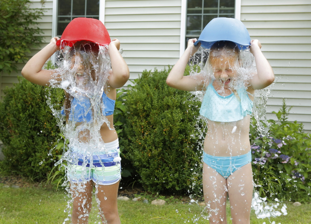 Matilda Bordas, left, and Rowan Pow, both 9, dump buckets of ice and water on their heads in Bordas' front yard in Kennebunk. The two girls were nominated by a friend in the ALS Ice Bucket Challenge that is using social media to raise funds for Amyotrophic lateral sclerosis, or Lou Gehrig's Disease.