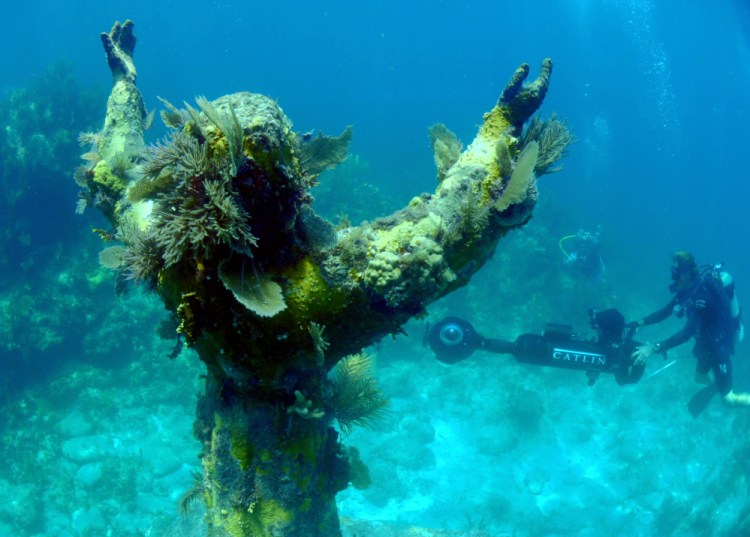 In this Aug, 6, 2014 photo provided by Catlin Seaview Survey, Catlin’s Christophe Bailhache surveys “Christ of the Abyss,” with the SVII cameras off the coast of Key Largo, Fla.