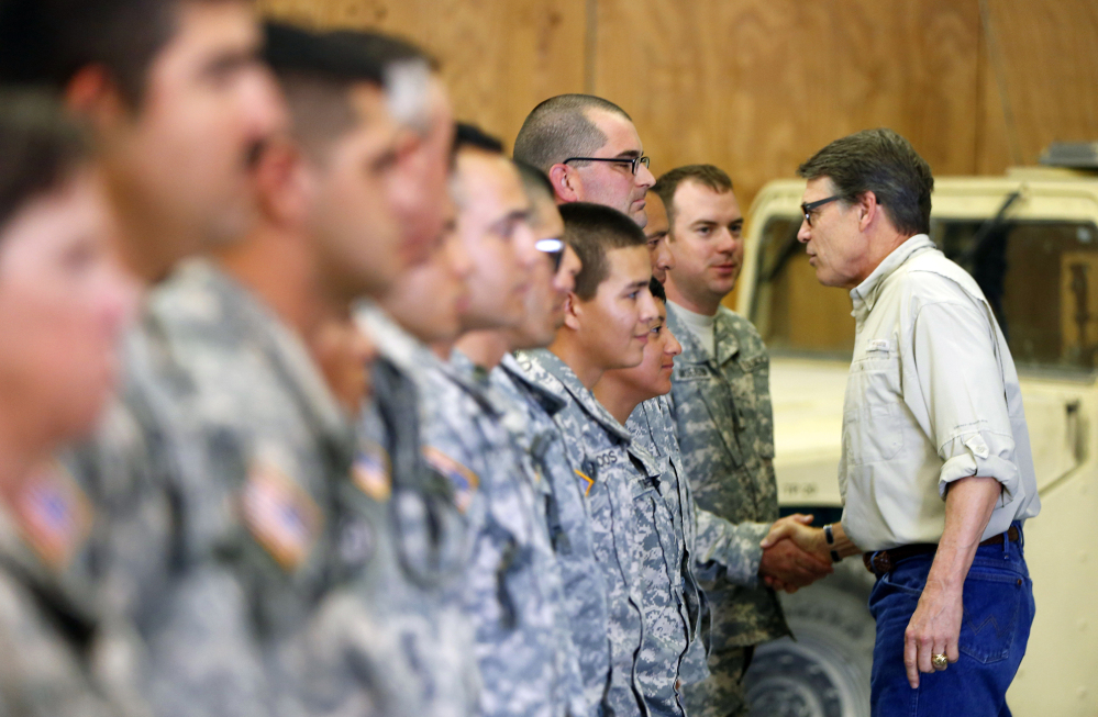 Gov. Rick Perry shakes hands with National Guard troops training at Camp Swift in Bastrop, Texas, on Wednesday.