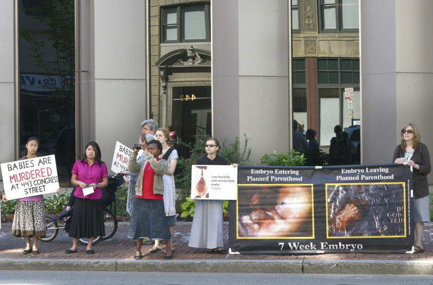 Anti-abortion protesters stand across the street from the Planned Parenthood clinic at 443 Congress St. in Portland. The city’s 39-foot no-protest buffer zone was lifted July 7.