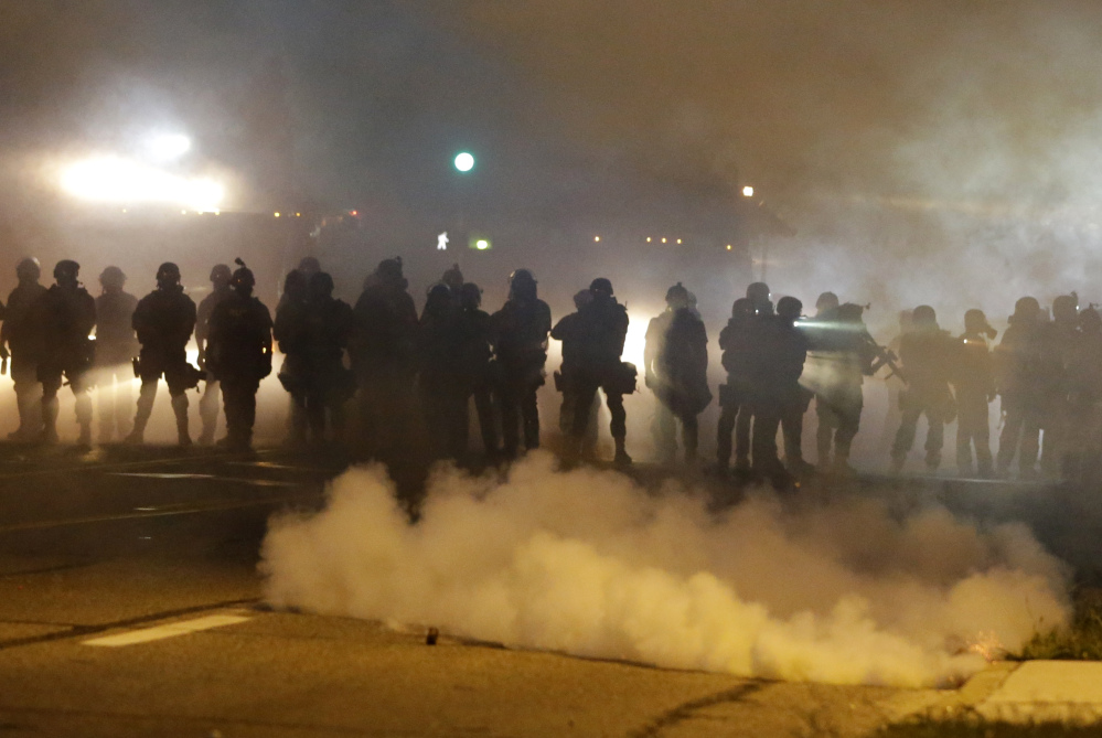 Police advance through smoke Wednesday night in Ferguson, Mo. “An undertow (of racial unrest) has bubbled to the surface,” said Police Chief Thomas Jackson.