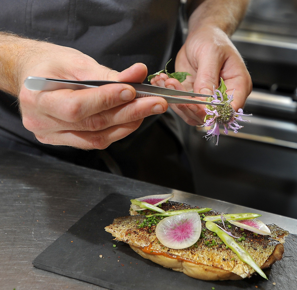 Chris Gould of Central Provisions garnishes his grilled Maine sardine crostini with sliced radish and flower petals and leaves.