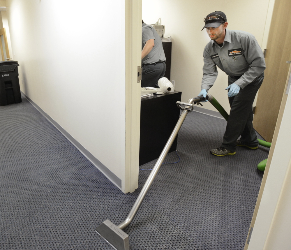 Christopher Steckino of Servpro cleans flooded offices on Main Street in South Portland on Thursday.